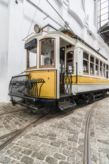 Perspective view of the old yellow tram with wooden windows and open driver cab. Vintage portugal city transport