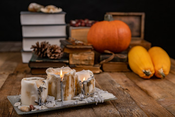 Old books, pumpkin and candles on a wooden desk. Workplace for the writer in an old study.