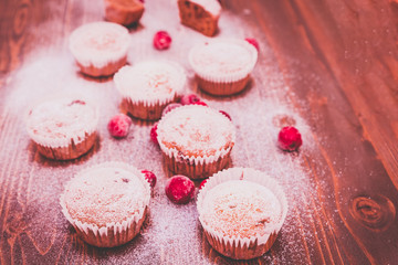some sweet muffins with sugar and cherries on a wooden background