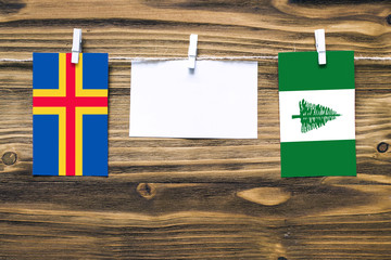 Hanging flags of Aland Islands and Norfolk Island attached to rope with clothes pins with copy...