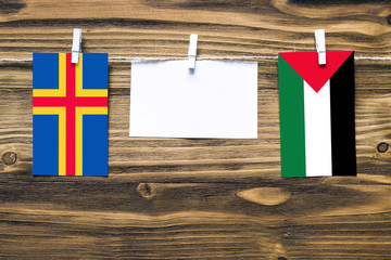 Hanging flags of Aland Islands and Palestine attached to rope with clothes pins with copy space on...