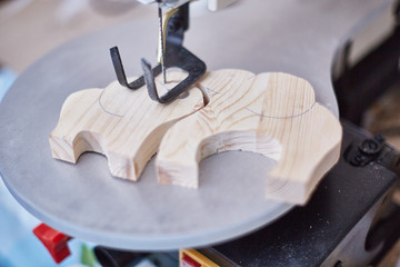 electric jigsaw with wooden elephants. Shallow depth of field. Focus on elephants. creation of...
