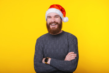 Portrait of young smiling man wearing santa claus hat with crossed arms looking confident at the camera