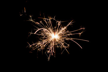 burning sparkler and flying sparks on a black background, festive sparkler