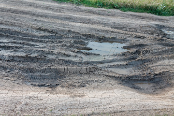 broken dirty rural road with large pits and ruts from cars, road repair and asphalt laying