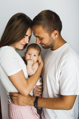 Happy young parents holding their baby and looking at her