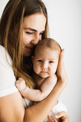 Young mother holding her little baby. Closeup portrait on white background.