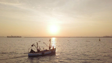 Naklejka premium Fishing boat on the background of golden sunrise. 