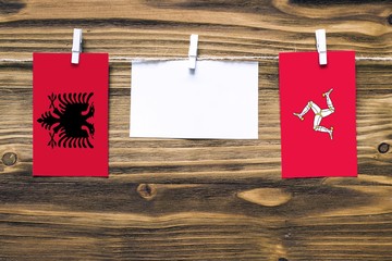 Hanging flags of Albania and Isle Of Man attached to rope with clothes pins with copy space on...
