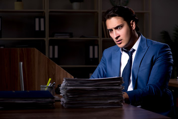 Young male employee working night in the office
