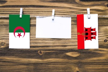 Hanging flags of Algeria and Gibraltar attached to rope with clothes pins with copy space on white...