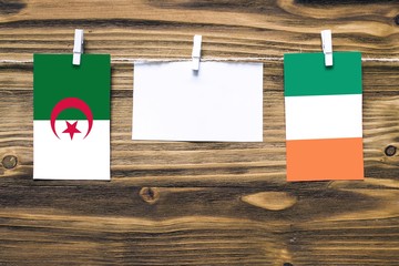 Hanging flags of Algeria and Ireland attached to rope with clothes pins with copy space on white...