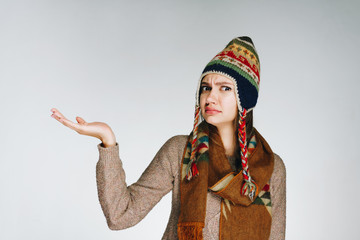 the girl frowns perplexedly and holds her outstretched palm. gray background