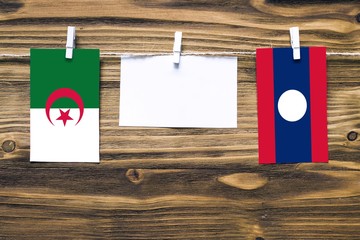 Hanging flags of Algeria and Laos attached to rope with clothes pins with copy space on white note...