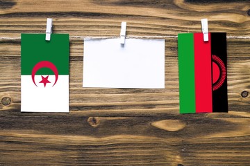 Hanging flags of Algeria and Malawi attached to rope with clothes pins with copy space on white...