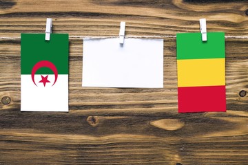 Hanging flags of Algeria and Mali attached to rope with clothes pins with copy space on white note...