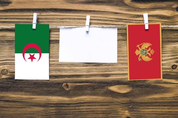 Hanging flags of Algeria and Montenegro attached to rope with clothes pins with copy space on white...