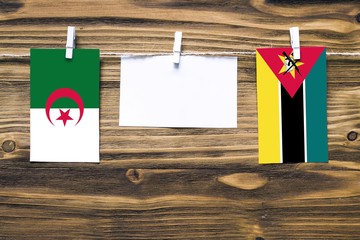 Hanging flags of Algeria and Mozambique attached to rope with clothes pins with copy space on white...