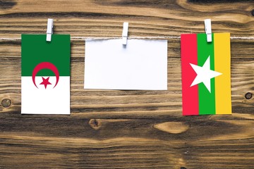 Hanging flags of Algeria and Myanmar attached to rope with clothes pins with copy space on white...