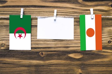 Hanging flags of Algeria and Niger attached to rope with clothes pins with copy space on white note...