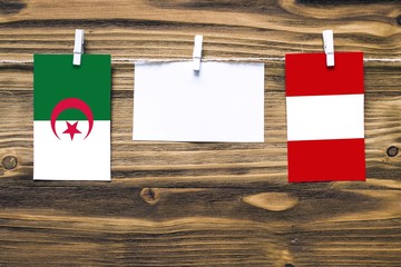 Hanging flags of Algeria and Peru attached to rope with clothes pins with copy space on white note...