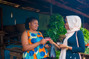 market woman receiving credit card from her customer  to pay her bills