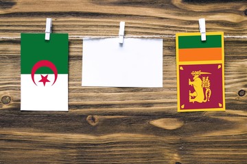 Hanging flags of Algeria and Sri Lanka attached to rope with clothes pins with copy space on white...