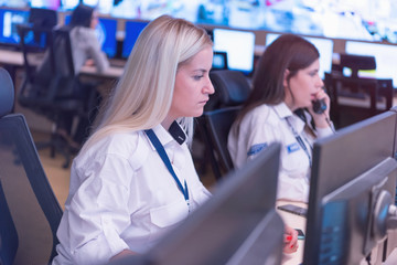 Security guard monitoring modern CCTV cameras in surveillance room. Two Female security guards in...