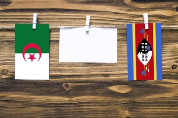 Hanging flags of Algeria and Swaziland attached to rope with clothes pins with copy space on white...