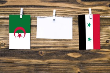 Hanging flags of Algeria and Syria attached to rope with clothes pins with copy space on white note...