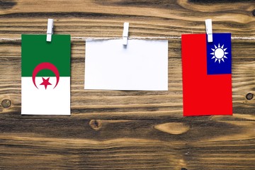 Hanging flags of Algeria and Taiwan attached to rope with clothes pins with copy space on white...
