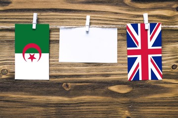 Hanging flags of Algeria and United Kingdom attached to rope with clothes pins with copy space on...