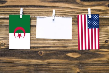 Hanging flags of Algeria and United States attached to rope with clothes pins with copy space on...