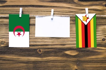 Hanging flags of Algeria and Zimbabwe attached to rope with clothes pins with copy space on white...