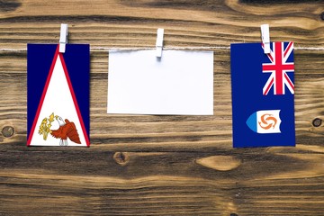 Hanging flags of American Samoa and Anguilla attached to rope with clothes pins with copy space on...