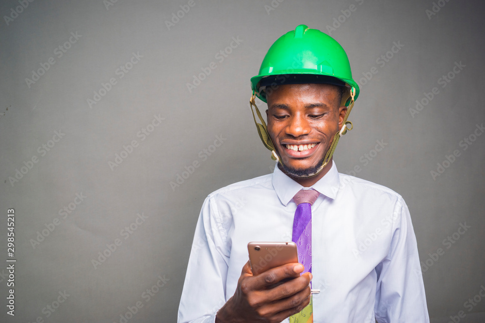 Wall mural a young nigerian engineer feeling excited as he holds his phone