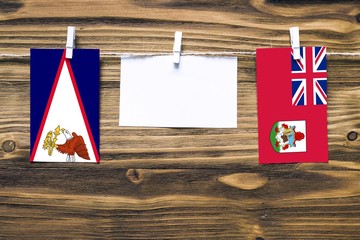 Hanging flags of American Samoa and Bermuda attached to rope with clothes pins with copy space on...