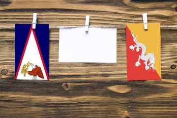 Hanging flags of American Samoa and Bhutan attached to rope with clothes pins with copy space on...