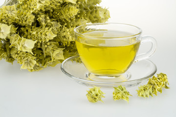 Bunch of mountain tea Malotira and mug with hot tea. Greek traditional herbal tea in transparent cup. Mountain tea sideritis. Natural Greek herbs.