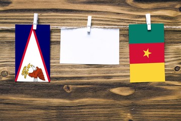 Hanging flags of American Samoa and Cameroon attached to rope with clothes pins with copy space on...