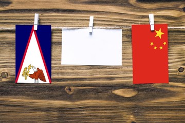 Hanging flags of American Samoa and China attached to rope with clothes pins with copy space on...
