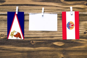 Hanging flags of American Samoa and French Polynesia attached to rope with clothes pins with copy...