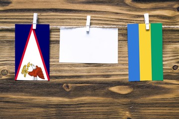 Hanging flags of American Samoa and Gabon attached to rope with clothes pins with copy space on...