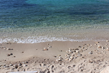 Sandstrand mit Steinen - blaues Meer