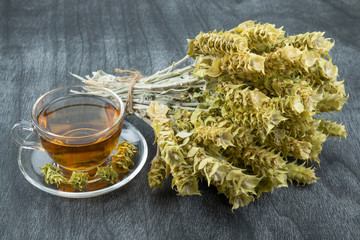 Greek traditional herbal tea in transparent cup. Bunch of mountain tea Malotira and mug with hot...