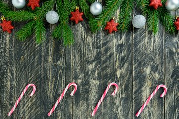 Christmas decorations, white balls and candy cane on a gray wooden table. Top view, copy space.