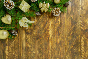Christmas decorations, golden color balls and pine cones on a brown wooden table. Top view, copy space.