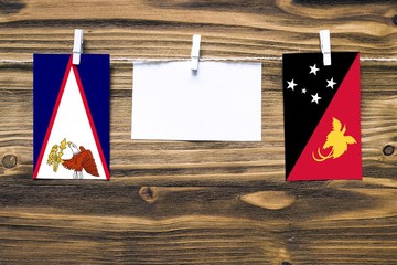 Hanging flags of American Samoa and Papua New Guinea attached to rope with clothes pins with copy...