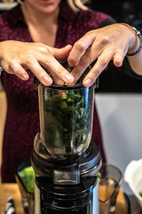 Obraz na płótnie Canvas Woman preparing a healthy green juice in a blender.