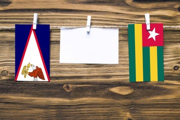 Hanging flags of American Samoa and Togo attached to rope with clothes pins with copy space on...